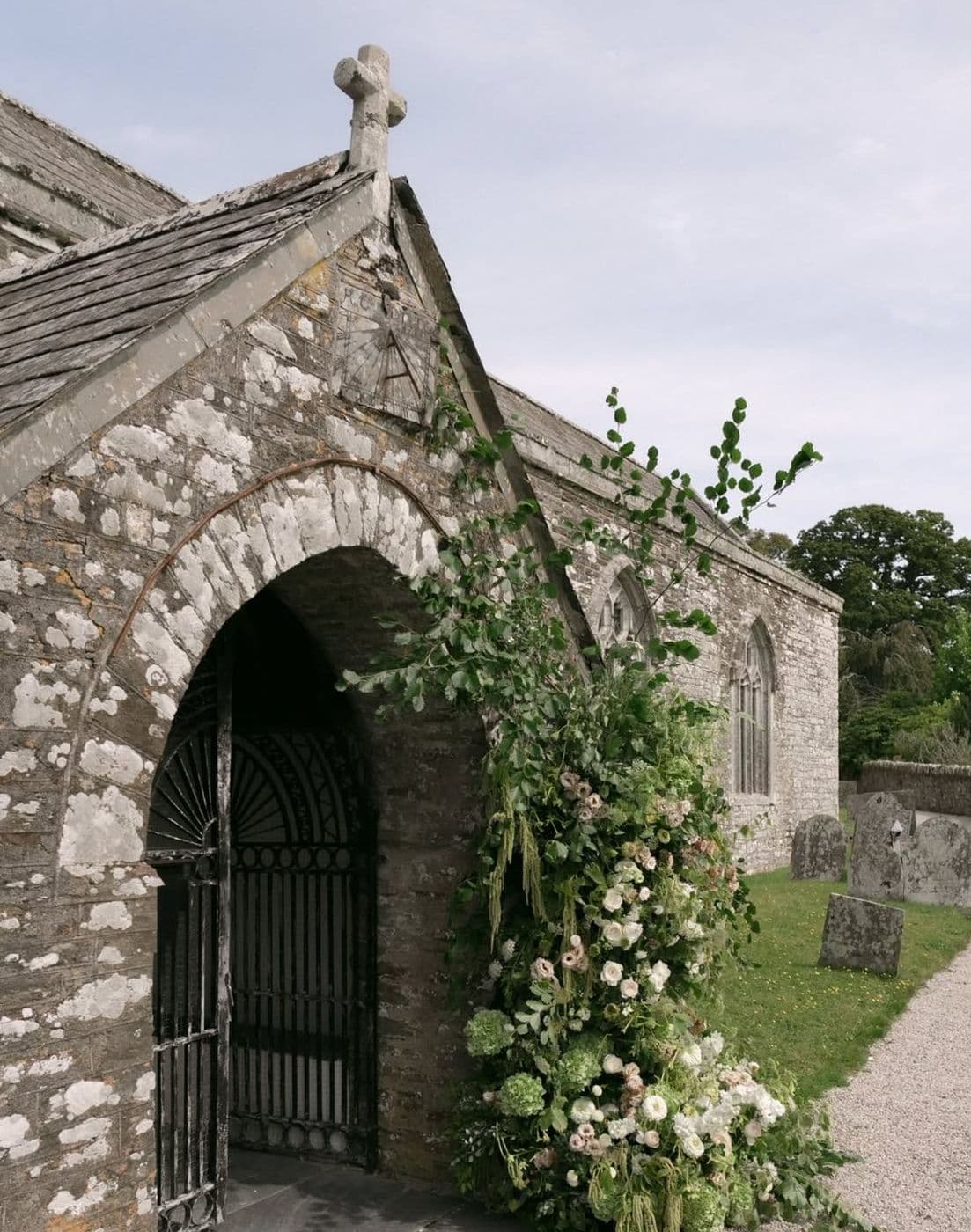 A stone chapel entrance framed by a floral arch