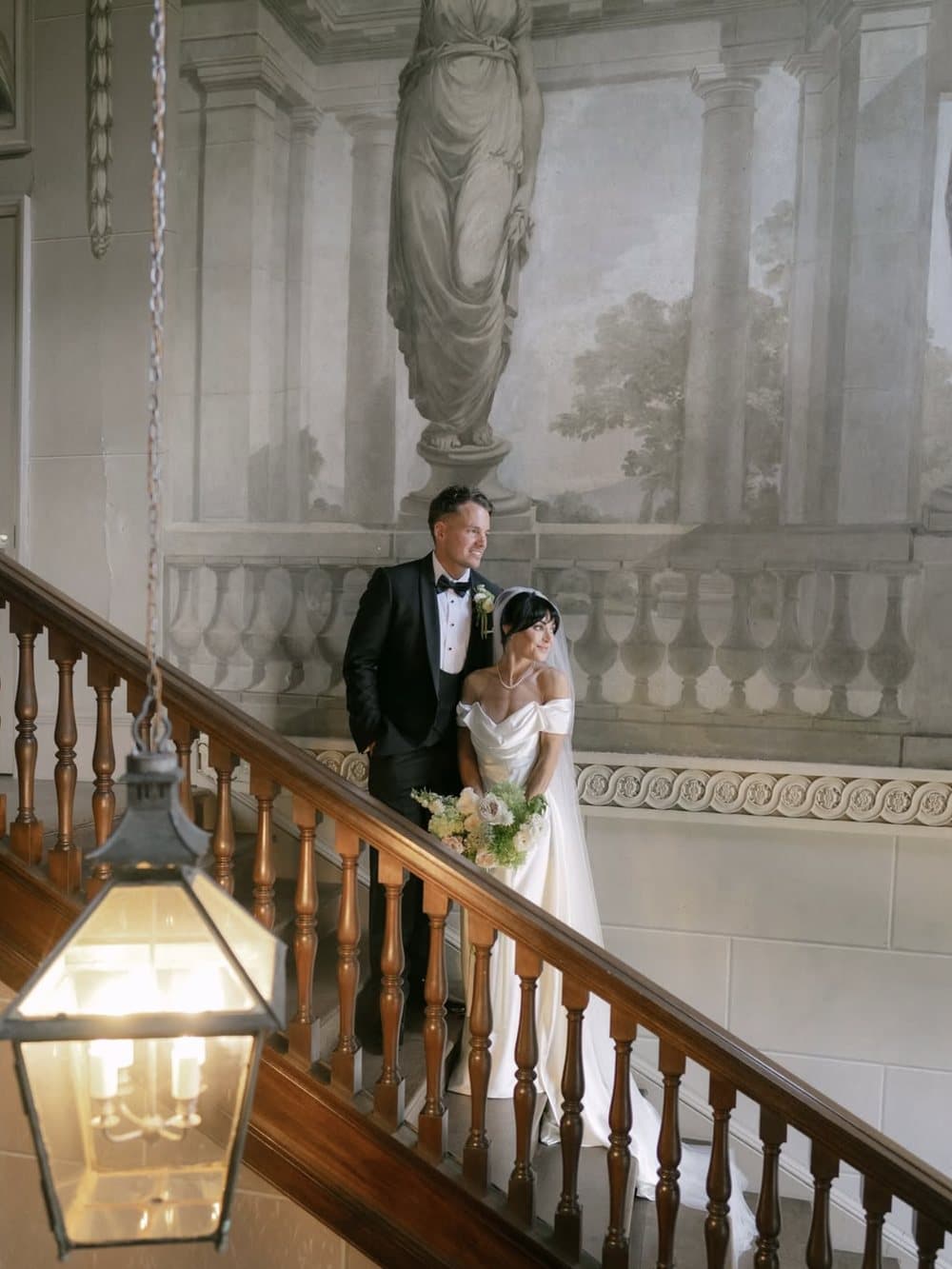 A couple pause together on a staircase beneath a painted mural