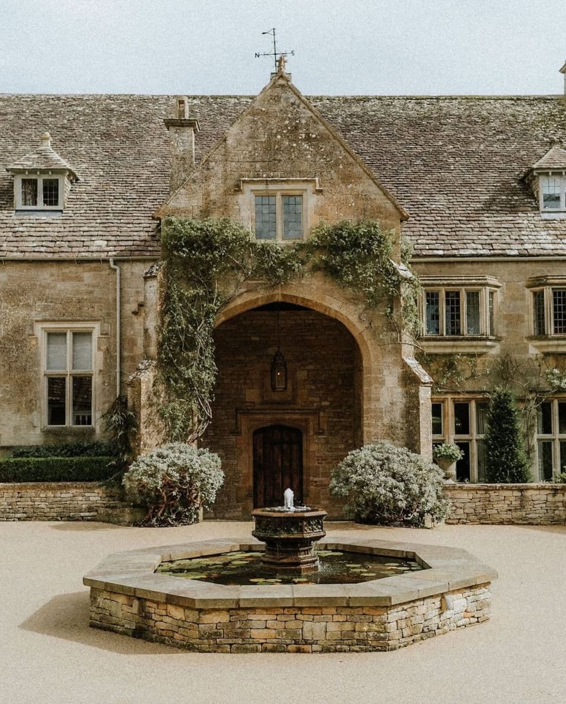A manor house with a fountain in the forecourt